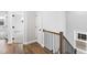 Hallway with hardwood floors, white trim, and an oak railing, leading to a bedroom with carpet at 100 Firefly Ln, Louisburg, NC 27549