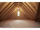 An unfinished attic space with exposed wooden beams, OSB subflooring, and a small window at 100 Firefly Ln, Louisburg, NC 27549