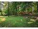 House nestled in a lush forest setting with a large green lawn at 4416 Arrowhead Trl, Hillsborough, NC 27278