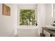 Spa-like bathroom featuring a free-standing tub and a serene view from a large window at 4416 Arrowhead Trl, Hillsborough, NC 27278