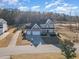 Aerial view of the gray home with a three-car garage, a long driveway, and golf course views at 649 Riverwood Dr, Clayton, NC 27527