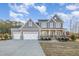 Charming two-story home with gray siding, a three-car garage, and a welcoming front porch at 649 Riverwood Dr, Clayton, NC 27527