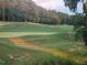 Beautiful, green golf course with a golf cart in the distance surrounded by a forest of trees at 649 Riverwood Dr, Clayton, NC 27527