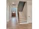 Bright hallway with hardwood floors leading to a wood door and stairs with black and wood banisters at 649 Riverwood Dr, Clayton, NC 27527