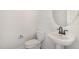 Elegant powder room featuring a toilet and a pedestal sink with a white circular mirror at 649 Riverwood Dr, Clayton, NC 27527