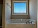 Bright bathroom featuring a soaking tub beneath a large window with blue sky views at 981 Olive Branch Dr, Smithfield, NC 27577