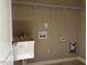 Well-lit laundry room with sink, washer and dryer hookups, and overhead shelving at 981 Olive Branch Dr, Smithfield, NC 27577
