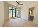 Bright bedroom featuring hardwood floors, large window, ceiling fan, and ensuite bathroom access at 7208 Tanbark Way, Raleigh, NC 27615