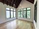 Sunlit dining area featuring hardwood floors, large windows with backyard views, and modern chandelier lighting at 7208 Tanbark Way, Raleigh, NC 27615
