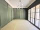 Dining room with olive green walls, wainscoting detail, chandelier, and black trimmed glass windows at 7208 Tanbark Way, Raleigh, NC 27615