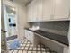 Bright laundry room features custom cabinets, black countertops and black and white patterned backsplash and floor tile at 7208 Tanbark Way, Raleigh, NC 27615