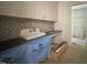 Laundry room featuring white cabinets, dark countertops, and unique tile backsplash at 7208 Tanbark Way, Raleigh, NC 27615