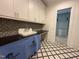 Well-lit laundry room features custom cabinetry, black countertops, and stylish backsplash and tile flooring at 7208 Tanbark Way, Raleigh, NC 27615