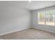 This bedroom features neutral carpeting, white trim, and a window with wooded scenery at 100 Bold Dr, Youngsville, NC 27596