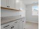 This laundry room features white cabinets, a tile floor, and a window with backyard views at 100 Bold Dr, Youngsville, NC 27596