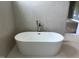 Modern bathroom features a freestanding soaking tub, light gray tiled wall, and floor at 126 Harvest Ln, Pittsboro, NC 27312