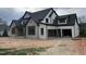 A modern farmhouse with stone accents, black trim, white siding, and a two-car garage under construction at 126 Harvest Ln, Pittsboro, NC 27312