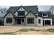 A modern farmhouse with stone accents, black trim, white siding, and a covered front porch under construction at 126 Harvest Ln, Pittsboro, NC 27312