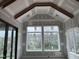 Bright living room featuring a vaulted ceiling, wooden beam, and large windows overlooking the backyard at 126 Harvest Ln, Pittsboro, NC 27312