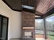 An outdoor brick fireplace with a wooden mantle under a dark wood ceiling and skylight at 126 Harvest Ln, Pittsboro, NC 27312