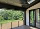 Covered porch with scenic view, features dark ceiling, fan, black railing, and access to backyard at 126 Harvest Ln, Pittsboro, NC 27312