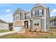 Charming two-story house with gray siding, stone accents, green grass and attached garage and landscaped front yard at 90 Bold Dr, Youngsville, NC 27596