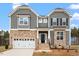 Inviting two-story home featuring stone accents, gray siding, well-manicured lawn, and an attached two-car garage at 90 Bold Dr, Youngsville, NC 27596