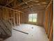 Unfinished bedroom featuring exposed wood framing, bare concrete, and a window, offering potential for custom design at 233 Jenkins St, Erwin, NC 28334