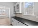 The butler pantry features upper glass cabinets, dark counters and a light backsplash at 2820 Lacy Holt Rd, Graham, NC 27253