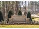 Stone entrance sign for Shadow Creek Estates is set among trees and plantings at 4804 Parker Meadow Dr, Raleigh, NC 27614