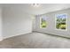 Bright bedroom with gray walls, neutral carpet, and two windows with a view of the trees at 484 Traditions Grande Blvd # 29, Wake Forest, NC 27587
