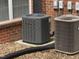 A Trane AC unit sits outside a brick building with window, alongside another AC unit and covered drain pipe at 129 Sturbridge Dr # 15, Clayton, NC 27520