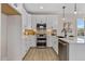 Updated kitchen with white cabinets, stainless steel appliances, island with seating, and tile backsplash at 2401 E Main St, Durham, NC 27703