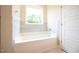 Bright bathroom featuring a built-in tub with tiled surround and a large window at 138 Abingdon Farms Dr, Selma, NC 27576