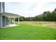 Spacious backyard with a covered porch and lush green grass with a view of the neighborhood at 236 Abingdon Farms Dr, Selma, NC 27576