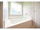 Bright bathroom featuring a deep soaking tub with ceramic tile surround and natural light at 236 Abingdon Farms Dr, Selma, NC 27576