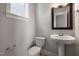 Stylish half bath with a pedestal sink, wood framed mirror, and modern fixtures for guests at 1660 Piney Falls Dr, Wendell, NC 27591