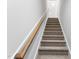 Carpeted staircase with wooden handrail leads to a white door, showcasing the home's design at 167 Thistle Ct, Sanford, NC 27332