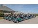 A row of golf carts is parked neatly on a paved surface near a building and grassy area at , Pittsboro, NC 27312