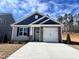 Charming single-story home featuring a gray exterior, a blue gable, stone accents, and a concrete driveway at 20 S Mistflower St, Clayton, NC 27520