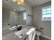 Well-lit bathroom with a large mirror, white countertops, a single sink, and a tiled shower/bath at 232 Bluejay St, Clayton, NC 27520