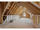 Unfinished attic space ready to be renovated with exposed wood framing and a window at 65 Cherry Bark Dr, Youngsville, NC 27596
