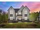 Striking exterior showcasing a modern two-story home with black-framed windows and lush green lawn at dusk at 65 Cherry Bark Dr, Youngsville, NC 27596