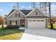 Charming home featuring a two-car garage, gray siding, stone accents, and well-maintained landscaping at 100 Carol Cir, Louisburg, NC 27549