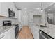 Bright kitchen with white cabinets, stainless steel appliances, granite counters, and wood flooring at 100 Carol Cir, Louisburg, NC 27549