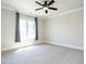 Carpeted bedroom with a ceiling fan, large window, and neutral walls provides a serene and comfortable atmosphere at 123 Cottage Way, Pittsboro, NC 27312
