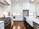 Well-lit kitchen featuring white cabinets, stainless steel appliances, an undermount sink, and hardwood floors at 123 Cottage Way, Pittsboro, NC 27312