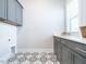 Charming laundry room has stylish tile flooring, grey cabinets, a sink, and window for natural light at 123 Cottage Way, Pittsboro, NC 27312