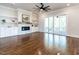 Open living room featuring hardwood floors, a ceiling fan, and a fireplace with built-in cabinets and shelving at 123 Cottage Way, Pittsboro, NC 27312