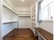 Spacious walk-in closet featuring custom shelves, cabinets, a bench, and hardwood floors at 123 Cottage Way, Pittsboro, NC 27312